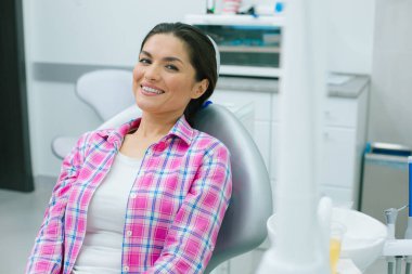 Tıbbi sandalyede oturan pozitif kadın ve gülümseyen tekerlek modern bir diş kliniğinde