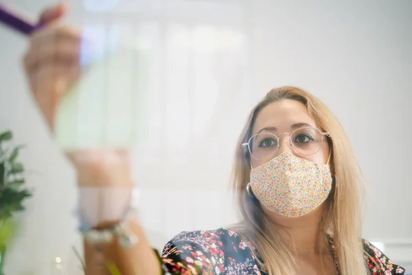 Jonge vrouw werkt in een kantoor met beschermend masker en sociale afstand — Stockfoto