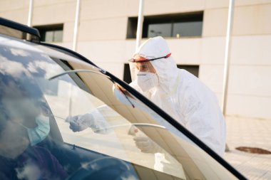 Doktor, arabanın camından bir hastaya PCR testi yapıyor.. 