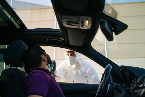 Doutor fazendo um teste de PCR COVID-19 em um paciente através da janela do carro. — Fotografia de Stock