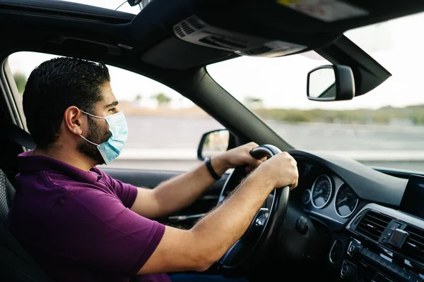 Man in een auto met een medisch masker tijdens een Covid-19 pandemie — Stockfoto