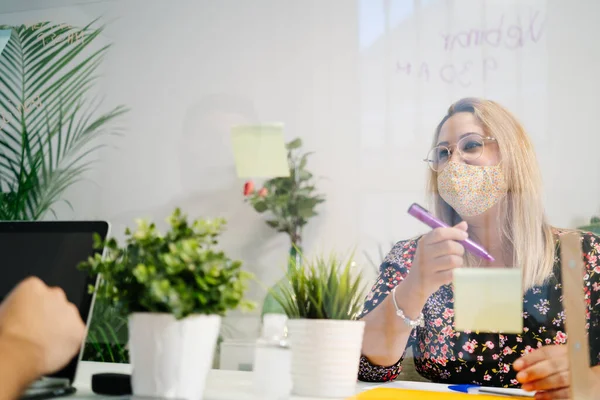 Giovane donna che lavora in un ufficio con maschera protettiva e distanza sociale — Foto Stock