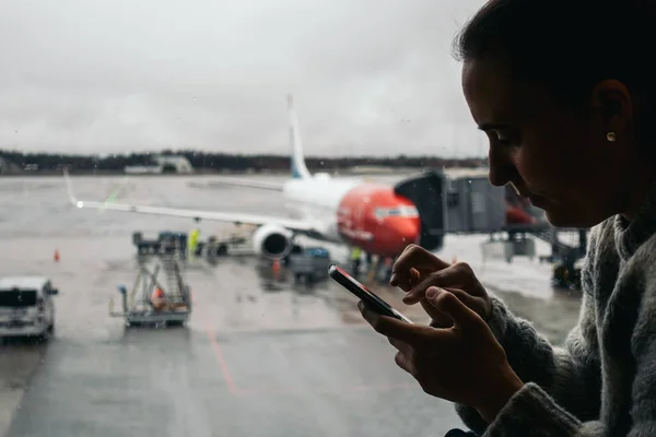 Nueva York, Estados Unidos - 27 de octubre de 2020: mujer esperando en el aeropuerto con su smartphone — Foto de Stock