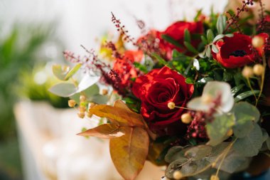 Çiçek arkaplan, doku. Kırmızı buket, çiçekçi tarafından hazırlanmış kırmızı güller, gelincikler ve okaliptüs yapraklarıyla yakın plan, makro