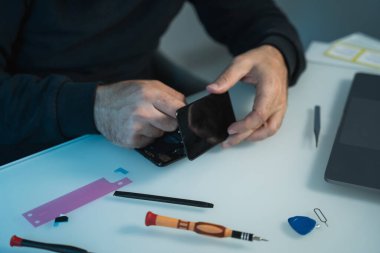 Masadaki yeni akıllı telefon ekranını tamir etmeye ve değiştirmeye hazırlanan teknisyen ya da mühendis
