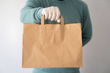 Paketten paket kağıdı alan bir adamdan kesilmiş görüntü. Yemek teslimatı konsepti. Coronavirus karantina konsepti