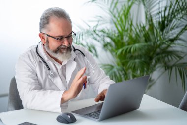 Bilgisayarda bir hastayla video konferansında doktor selamı. Telematik ya da çevrimiçi iş kavramı.