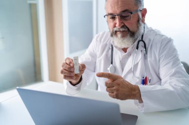 Bir kıdemli doktorun PCR test sonuçları Covid-19 'u gösteren bir hastayla görüntülü görüşme yaparken görüntülerini kapatın.