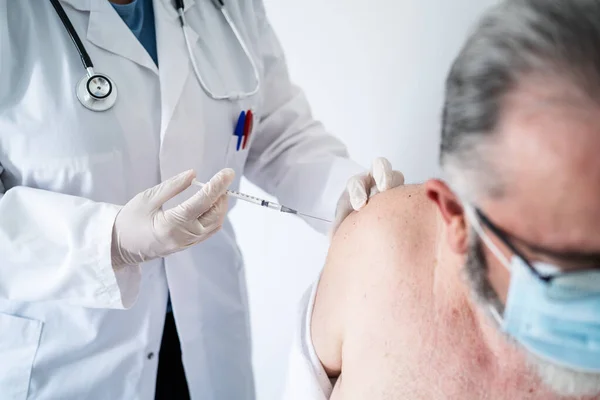 医者の閉鎖コヴィド-19ワクチンで外科マスクを持つ高齢者をワクチン接種 — ストック写真