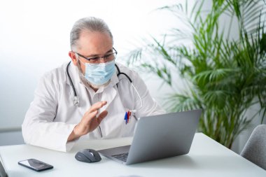 Kıdemli doktor bir hastayla bilgisayar konferansında görüşüyor. Telematik ya da çevrimiçi iş kavramı.