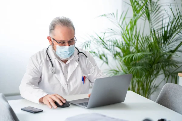 Doktor ofisinde dizüstü bilgisayarla çalışıyor. Telematik ya da çevrimiçi iş kavramı.