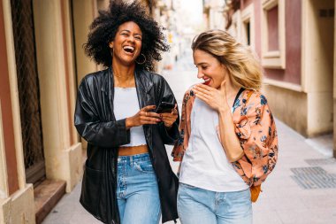 İki farklı kadın arkadaş şehrin bir caddesinde birlikte eğleniyorlar.