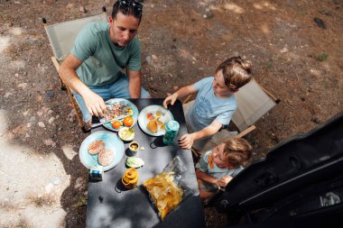 Aile piknik yapıyor, taşınabilir bir karavanın yanında.