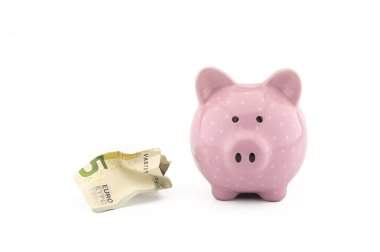 Avronun buruşuk banknotları ve beyaz üzerine pembe kumbaralar. Finansal veya tasarruf kavramları için kopyalama alanı var.