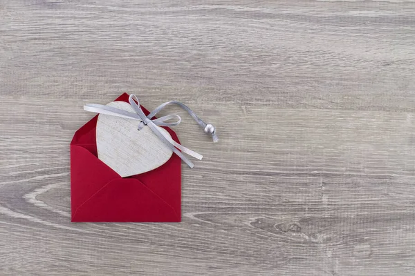 赤い封筒の中にハート型の木製のメダリオンが置かれています 挨拶と愛の手紙 — ストック写真