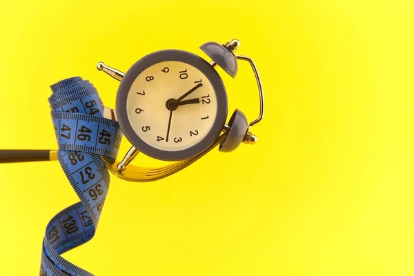 Reloj Despertador Horquilla Dorada Envuelta Con Cinta Métrica Sobre Fondo —  Fotos de Stock