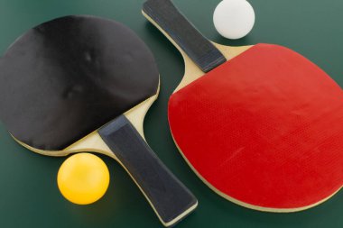 İki masa tenisi rafı, beyaz ve yeşil arka planda sarı ping pong topu ve bedava fotokopi alanı.