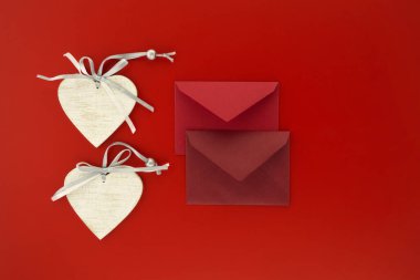 Kırmızı arka planda kalp madalyonları ve zarflar. Mesaj için boş yer var. Selamlar ve aşk mektubu.