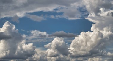 Dramatic sky with puffy white and gray clouds against a blue background. Perfect for backgrounds and weather themes.