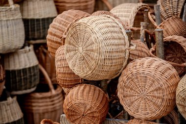 Round wicker baskets in natural tones, stacked on weathered wooden posts. Perfect for home decor, craft markets or rustic interiors, illustrating traditional basket weaving and artisanal craftsmanship
