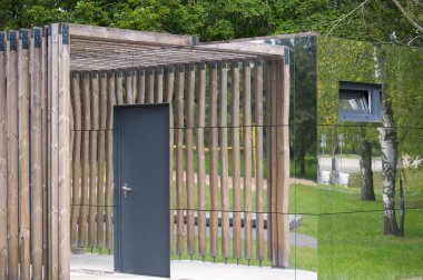 Çağdaş bir bina eşsiz bir tasarım sergiliyor, doğal ahşabı aynalı panellerle harmanlıyor, bir kapı ile görsel olarak çarpıcı bir etki yaratıyor..