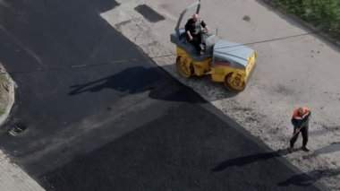 Küçük bir buharlı silindir yolda asfaltı dümdüz ediyor..