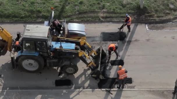 Werknemers gieten heet asfalt met schoppen op een straat. — Stockvideo