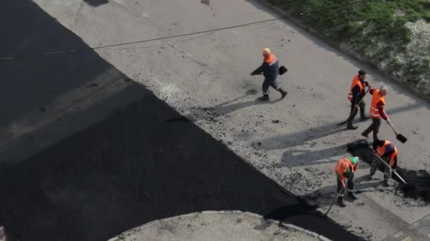 Dělníci nalévají horký asfalt s lopatami na ulici. — Stock video