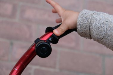 Birine çarpmamak için bisikletinin zilini çalan küçük bir çocuğun elini detaylandır.