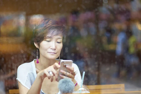 Uma beleza asiática olhando para smartphone no café — Fotografia de Stock