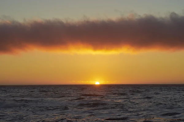 Ozean bei Sonnenuntergang mit Streifenwolke darüber — Stockfoto