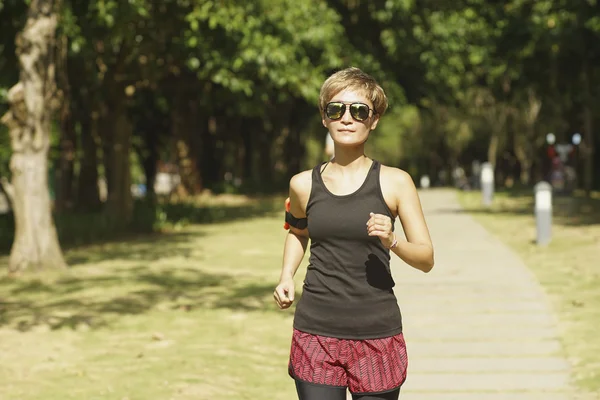 Asian woman running in sunshine in a city park
