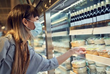 Maske takan Asyalı kadın salgın sırasında açık büfede salata yiyor.