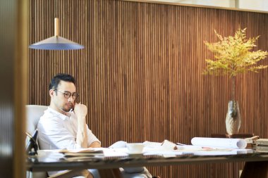 Masada çalışırken günlük kıyafet tasarlayan Asyalı tasarımcı
