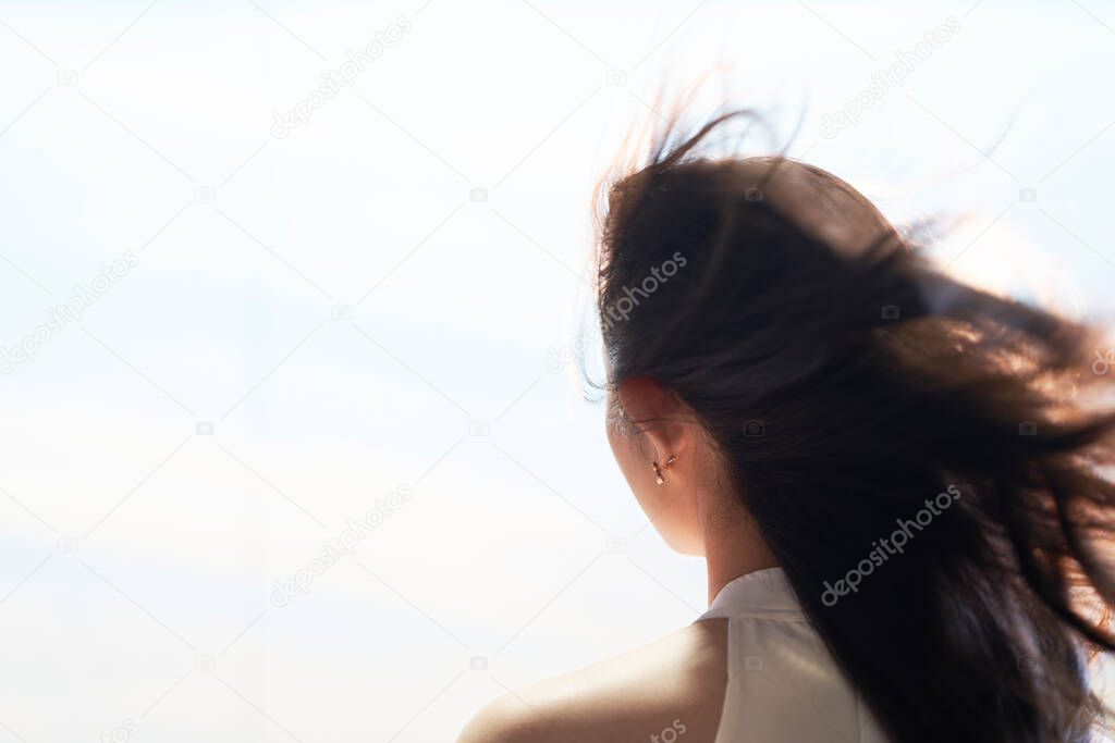 rear view of Asian beauty standing with wind blown long black hair