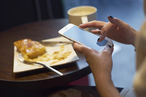 Meisje met behulp van mobiele telefoon bij het ontbijt — Stockfoto