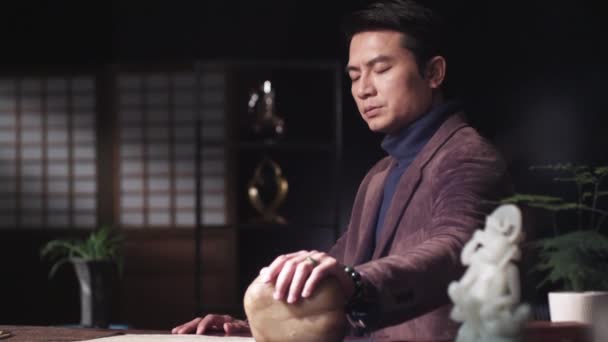 Un hombre asiático meditando en la habitación — Vídeo de stock
