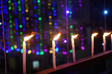 Balkon korkuluklarında parlayan beyaz mumlar renkli şenlik arka planında.