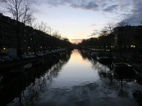 Naplemente Kilátás Egy Csatornára Amszterdamban Megvilágított Lámpákkal Felhős Égen — Stock Fotó