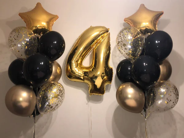 Composition of balloons of gold, black, balloons with confetti and a large foil balloon in - number 4