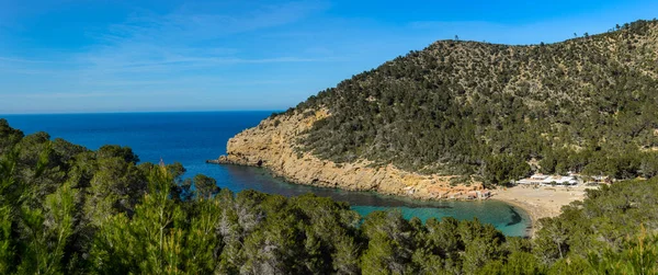 Benirras plajı, İbiza, İspanya - 31 Ocak 2020: Benirras plajının panoramik manzarası. Ibiza Adası 'nın kuzeyinde. Etrafı çam ormanlarıyla çevrili sahilde balıkçıların evleri ve birkaç restoran bulacaksınız. Cele 'nin davul partisi.