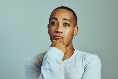 Eli çenesinde, ciddi düşünceli bir adam başka tarafa bakıyor.