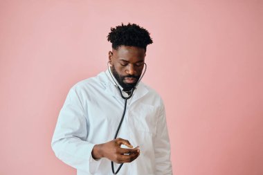 Düşünceli erkek cerrah pembe arka planda el ele bakıyor.