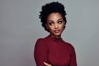 Düşünceli, güzel, kıvırcık saçlı, kırmızı süveter giyen Afro-Amerikan kadının göz kamaştırıcı portresi.