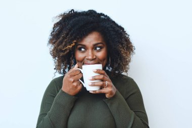Beyaz arka planda kahve içen orta yaşlı Afro kadının portresi