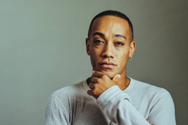 Eli çenesinde ciddi düşünceli bir adam kamera stüdyosuna bakıyor.