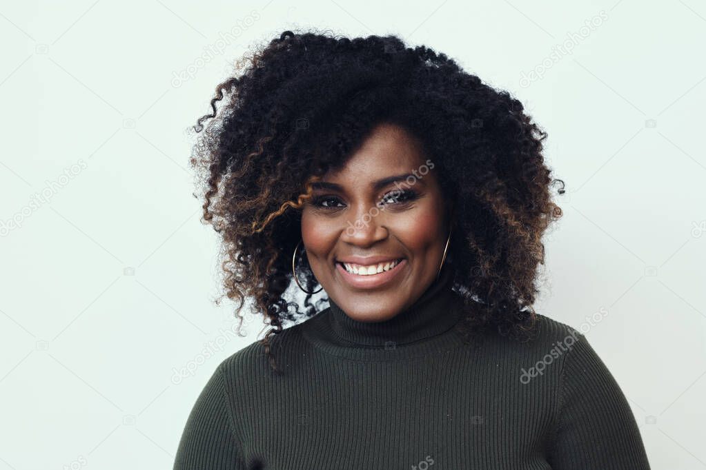 Portrait of happy beautiful young woman with curly hair green sweater against white background