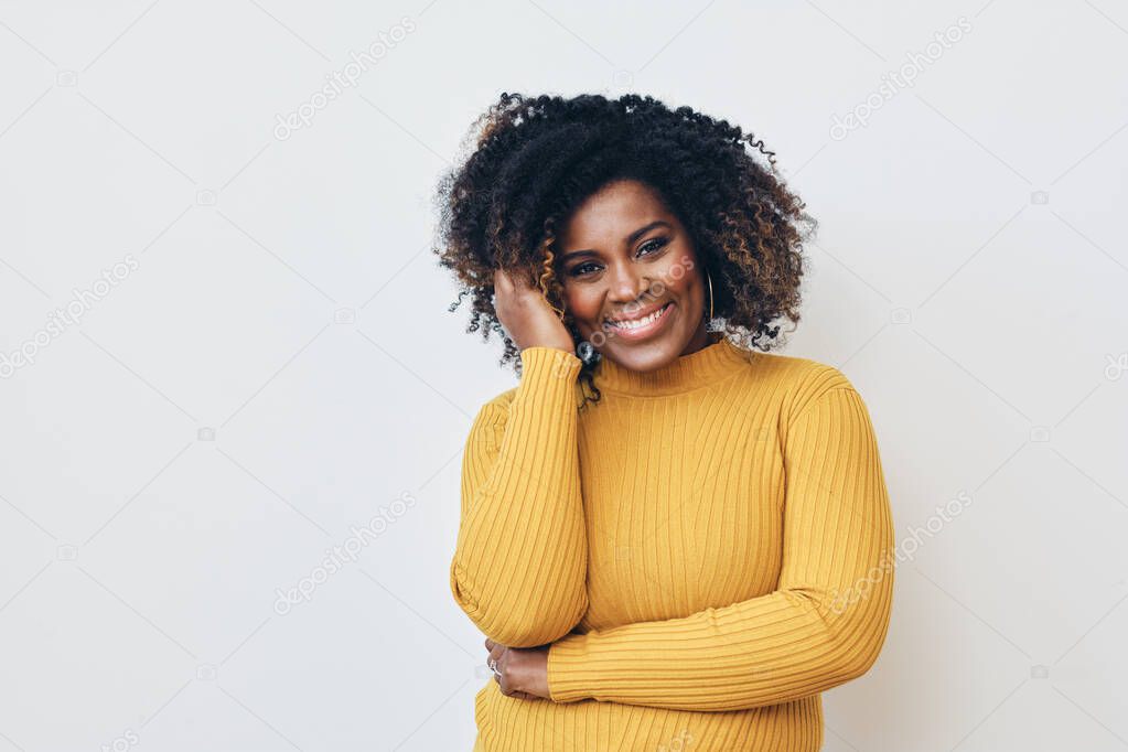 Portrait of smiling beautiful Afro woman standing with arms crossed, one hand in hair