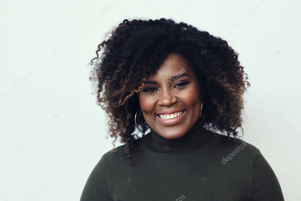 Portrait of happy beautiful young woman with curly hair green sweater against white background