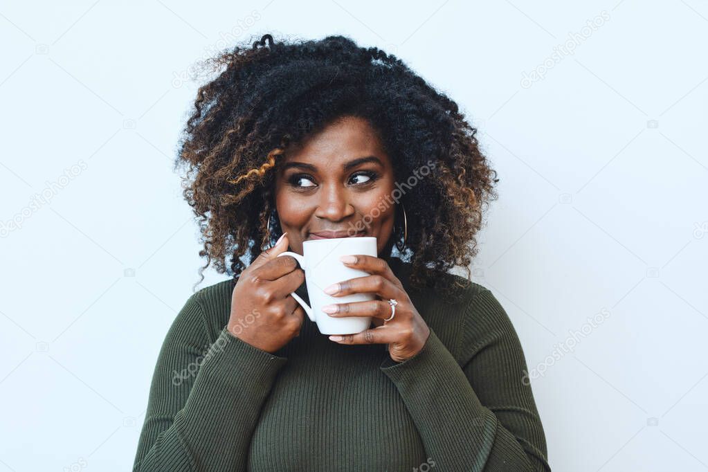 Portrait of smiling mid adult Afro woman drinking coffee against white background